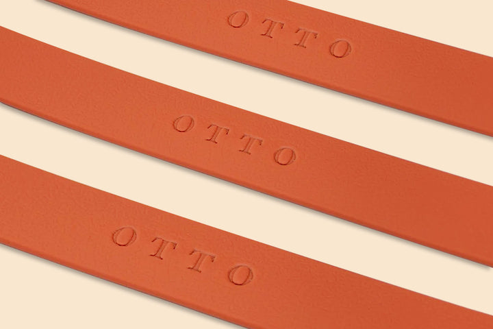 Close-up of three orange waterproof collars. The collars have the names embossed on them.