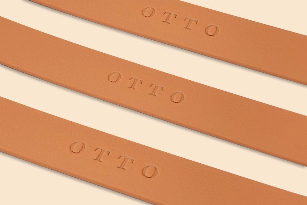 Close-up of three brown waterproof collars. The collars have the names embossed on them.