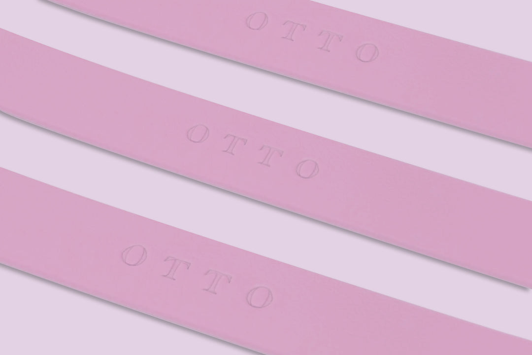 Close-up of three pink waterproof collars. The collars have the names embossed on them.