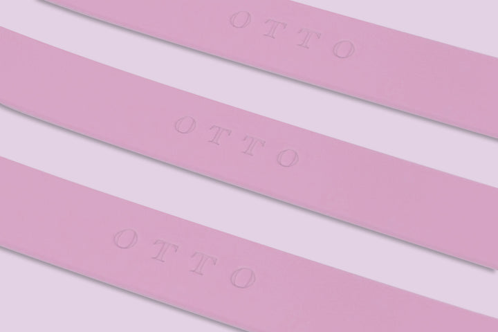 Close-up of three pink waterproof collars. The collars have the names embossed on them.