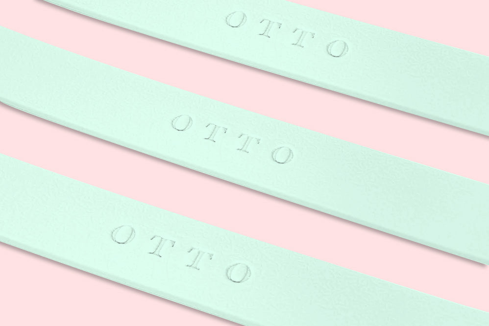 Close-up of three light green waterproof collars. The collars have the names embossed on them.